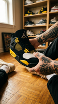 Main tatouée insérant un protège-plis dans une Jordan 4 Thunder